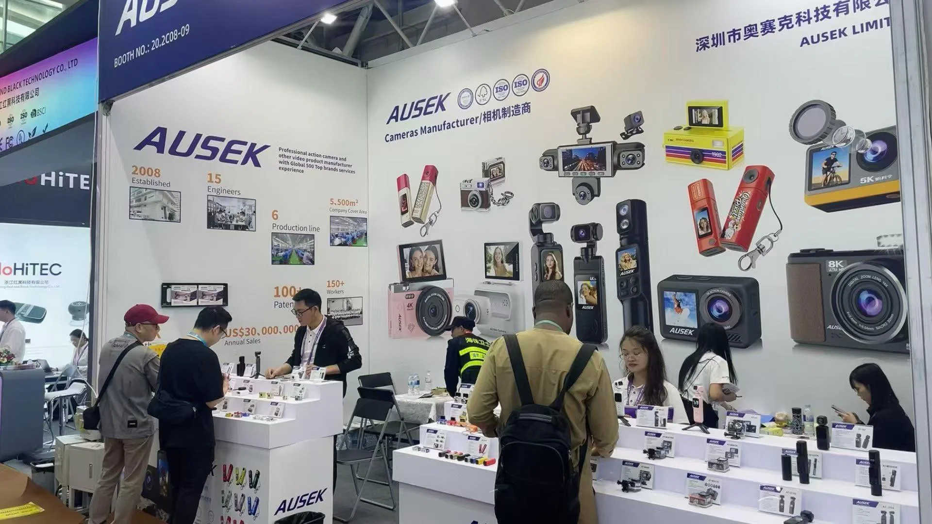 Camera displays and conversations at an AUSEK booth during a previous exhibition
