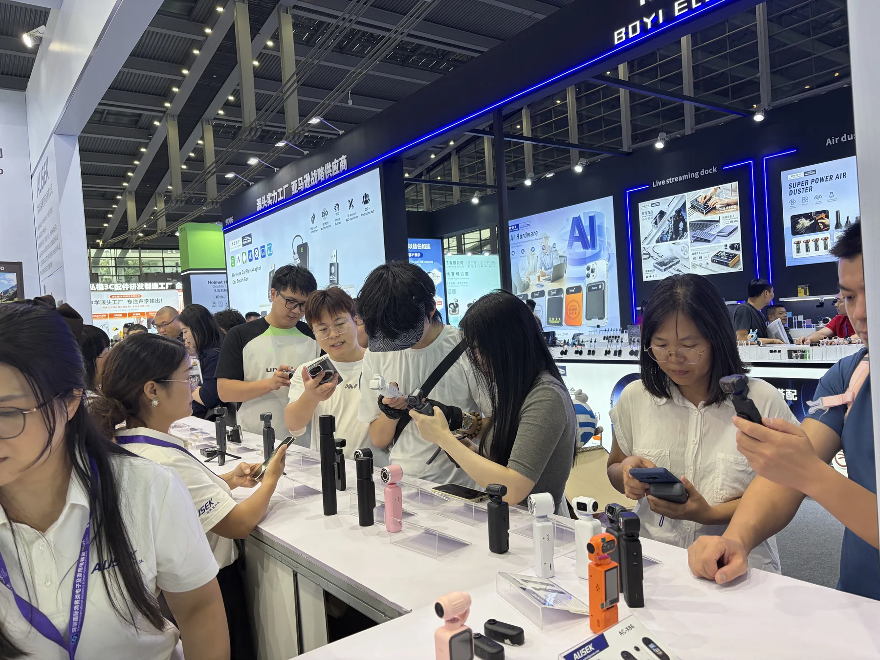 Visitors exploring cameras at an AUSEK exhibition stand.